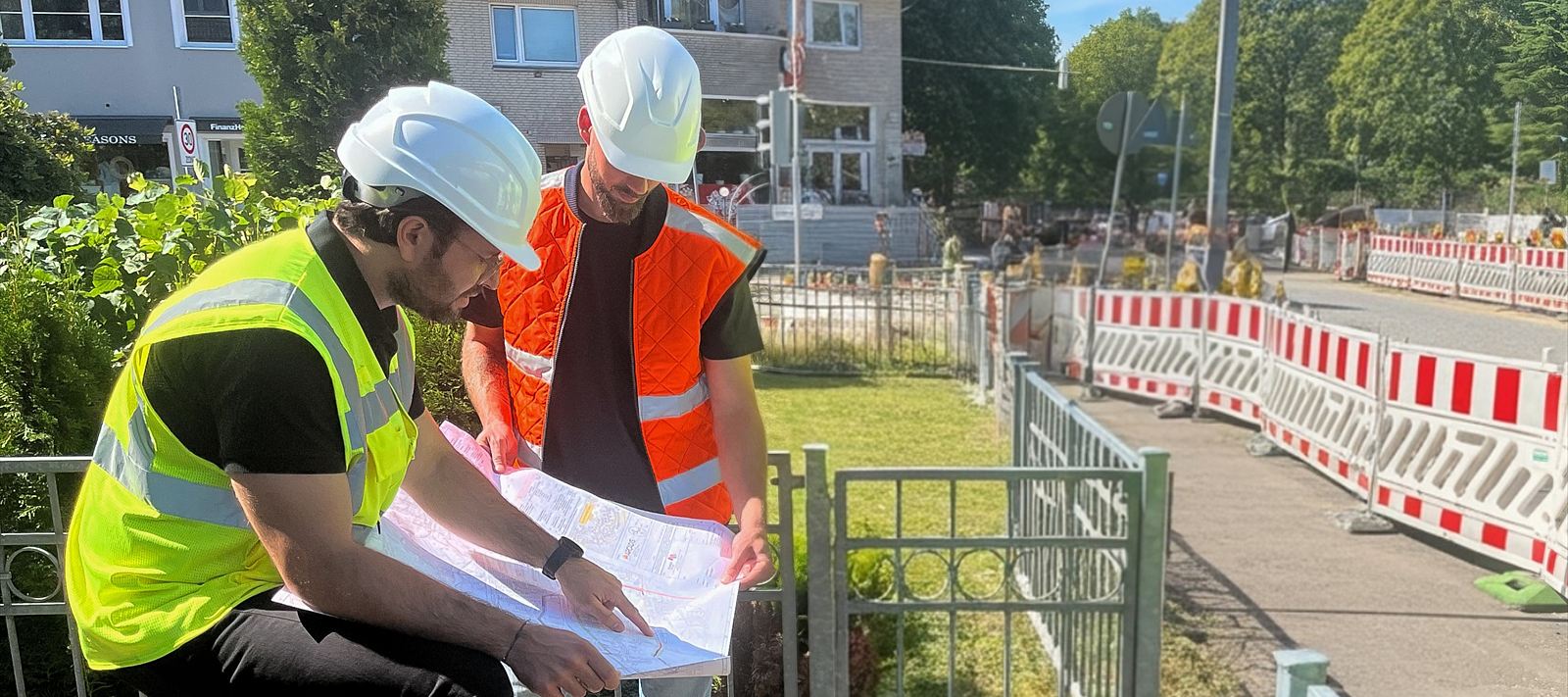 Pascal Oehlckers bespricht mit einem Fachkollegen die Planunterlagen bei einem Ortstermin auf einer Baustelle